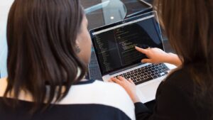 Two developers reviewing code together on a laptop