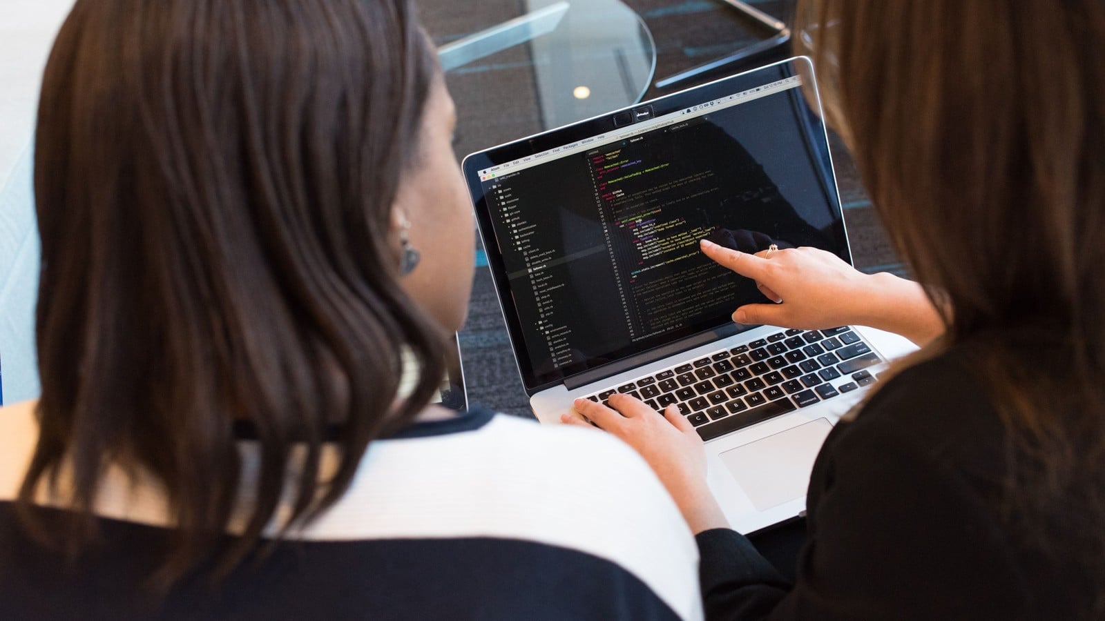 Two developers reviewing code together on a laptop