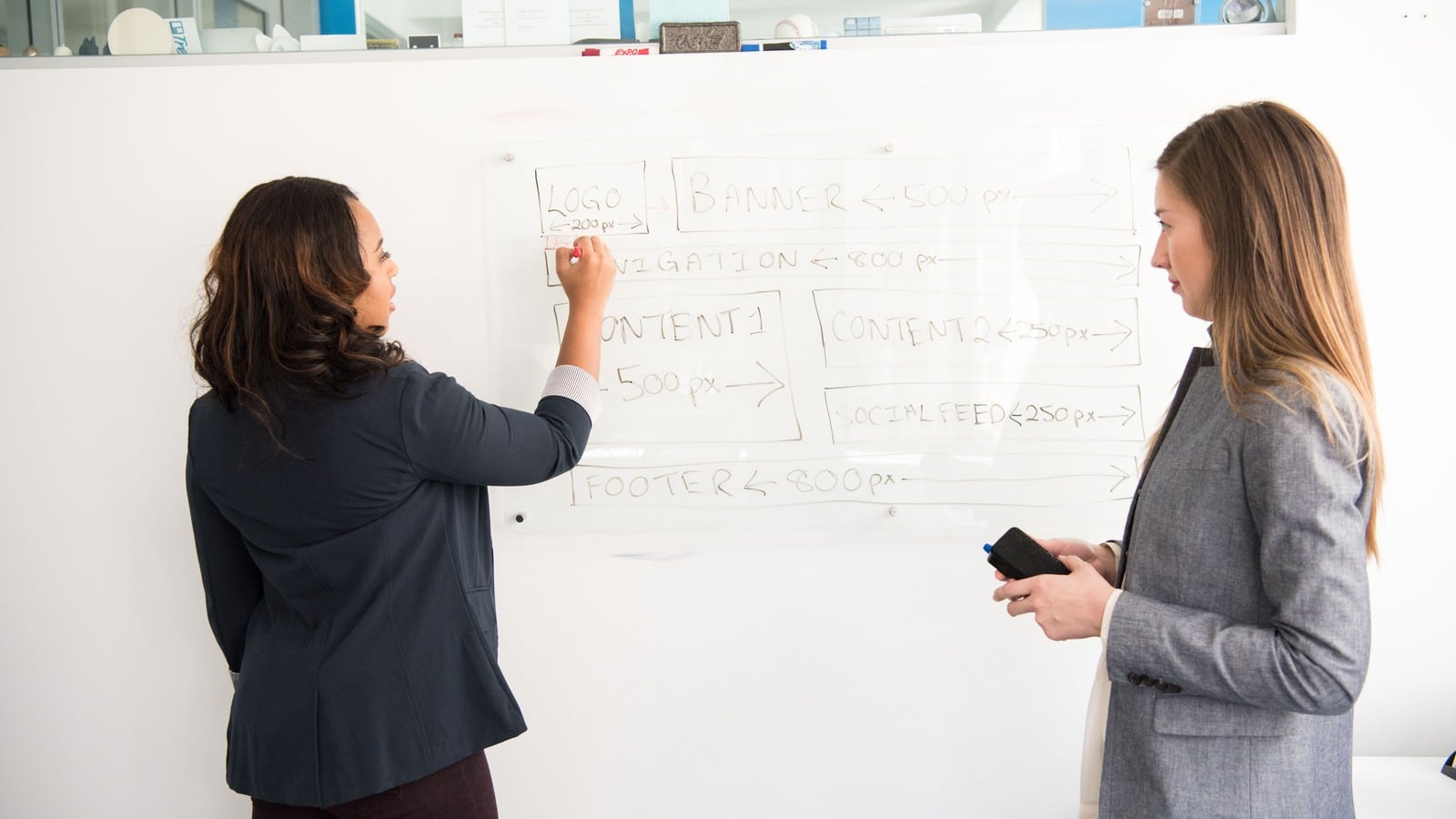Two colleagues planning a software interface on a whiteboard