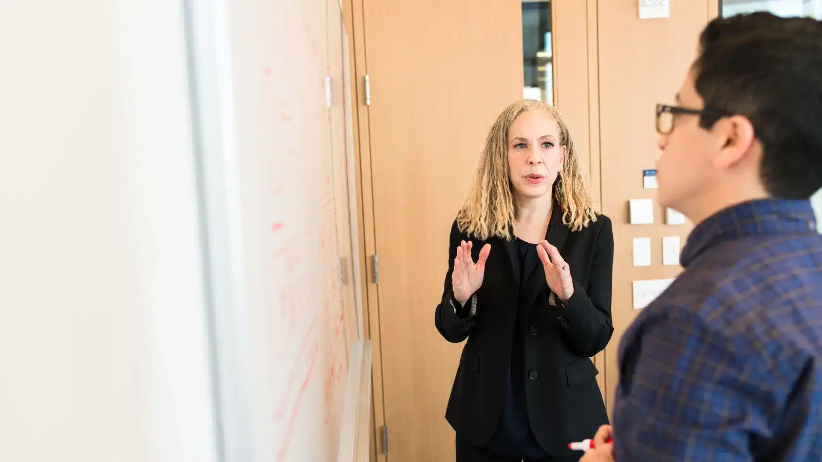 Two colleagues discussing a project beside a whiteboard.